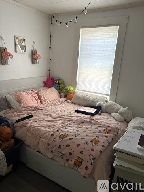 A bedroom with a bed covered in a pink comforter and a white teddy bear on the bed.