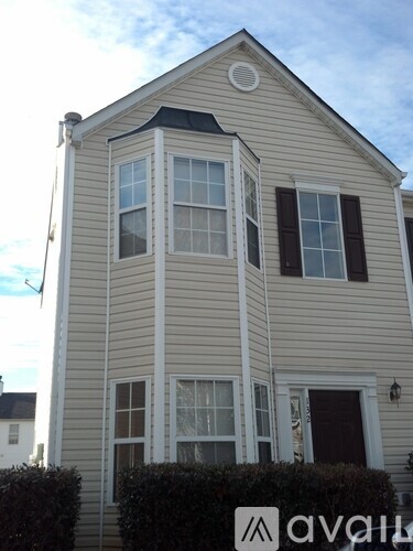 A two-story house with a white door and black shutters.