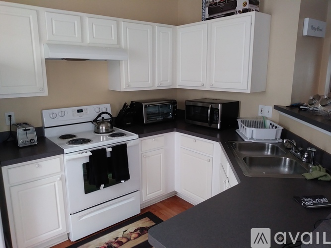 A kitchen with white cabinets and black countertops.