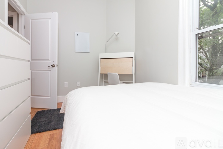 A bedroom with a white bed and a window.