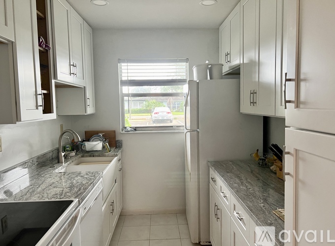 A kitchen with white cabinets and a marble countertop.