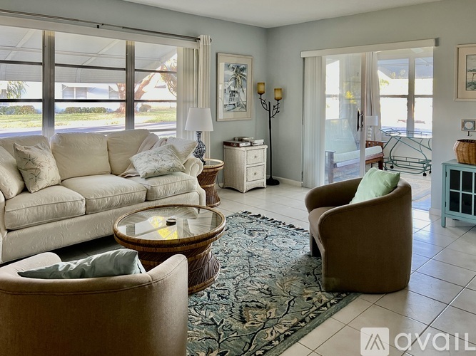 A living room with a white sofa, a brown armchair, and a glass table.