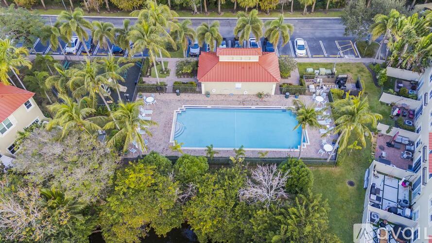 A pool surrounded by trees and a building with a red roof.