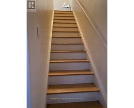 A staircase with wooden steps and white walls.