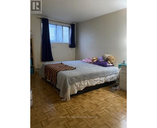 A bedroom with a bed, a window with curtains, and a teddy bear on the bed.