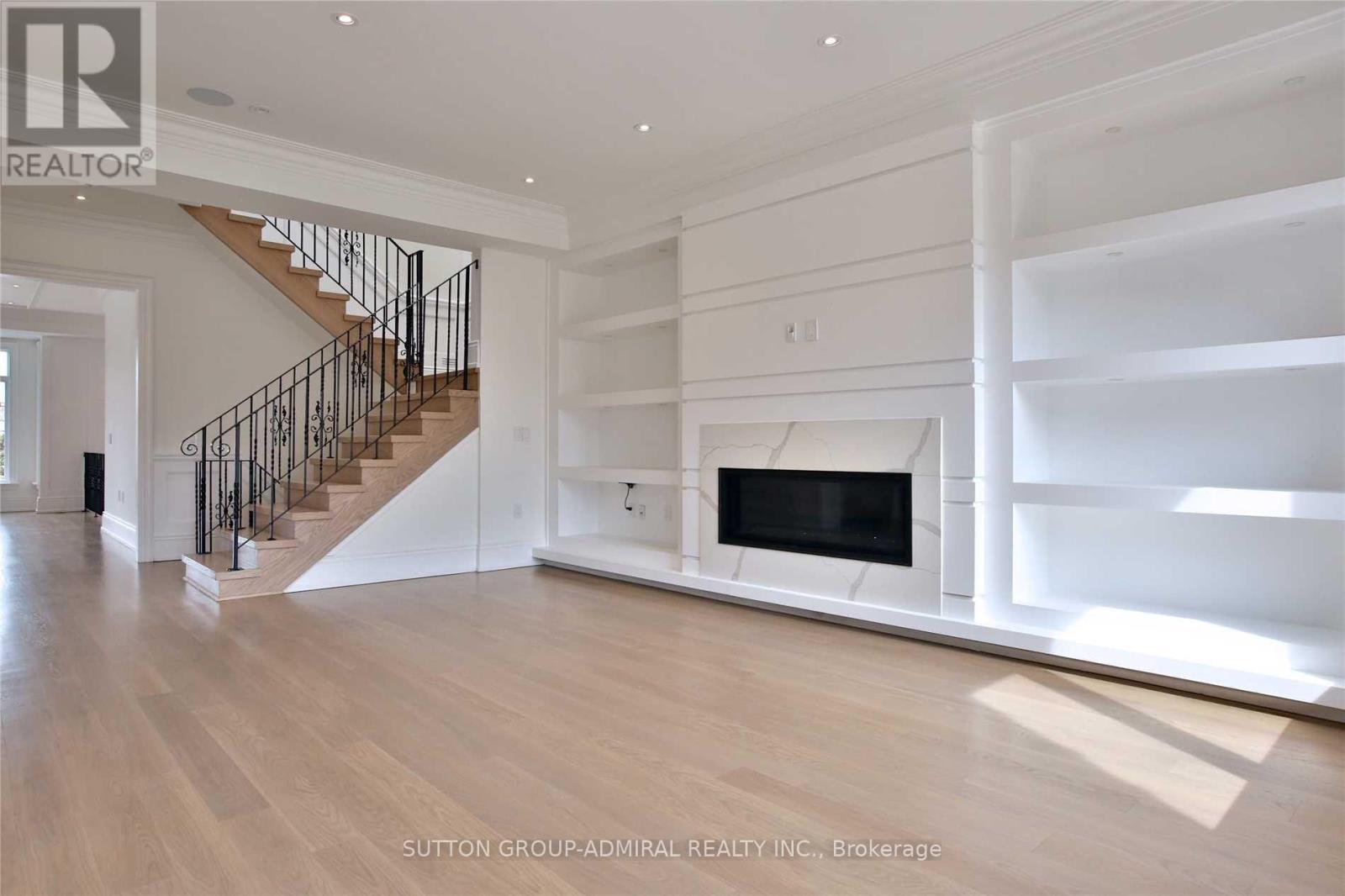 A spacious living room with a fireplace and a staircase.