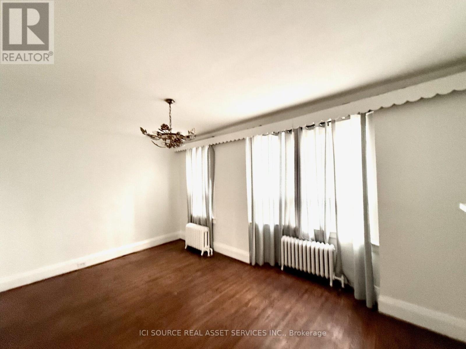 A room with a chandelier, curtains, and radiators.
