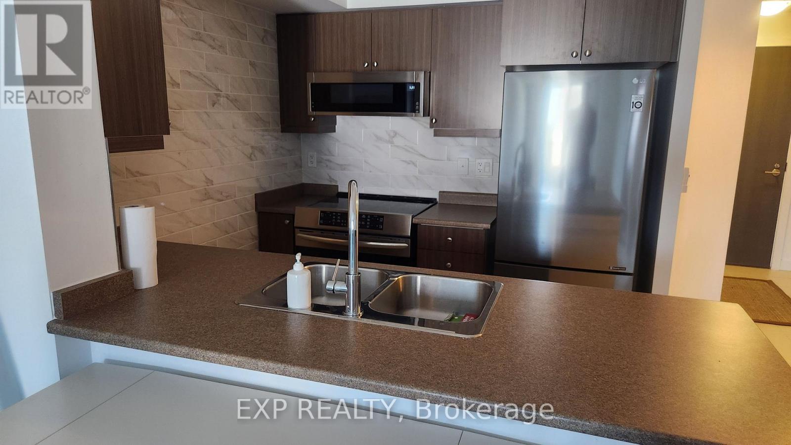 A kitchen with a stone backsplash and stainless steel appliances.