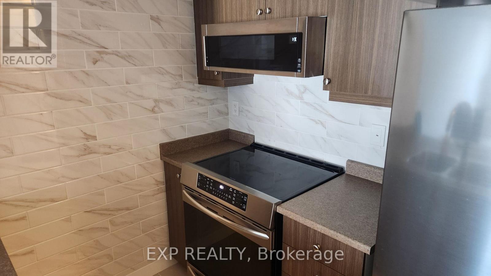 A kitchen with a stainless steel refrigerator and a microwave above the stove.