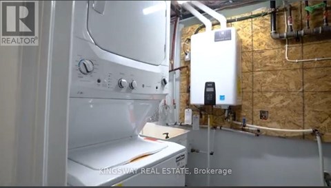 A white oven in a kitchen with a wall of pipes behind it.