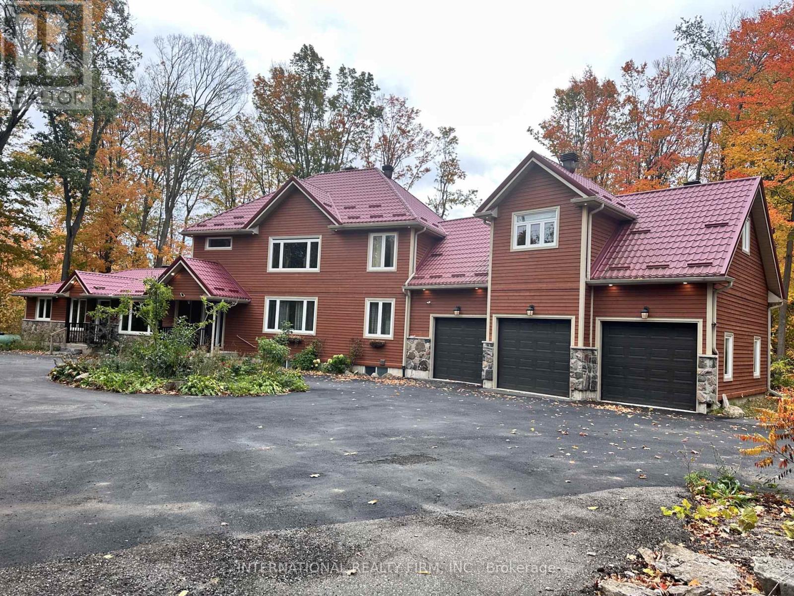 A large house with a red roof and a driveway in front.