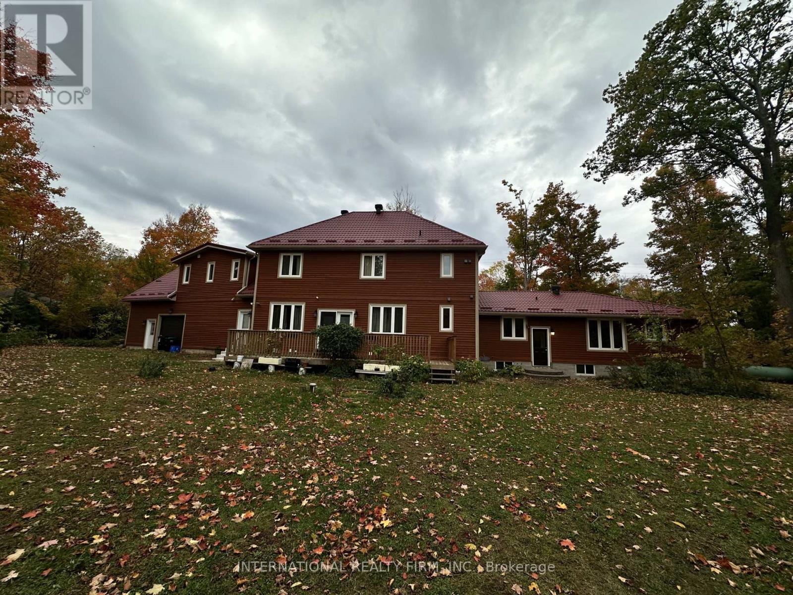 A house with a red roof and a lawn covered in fallen leaves.
