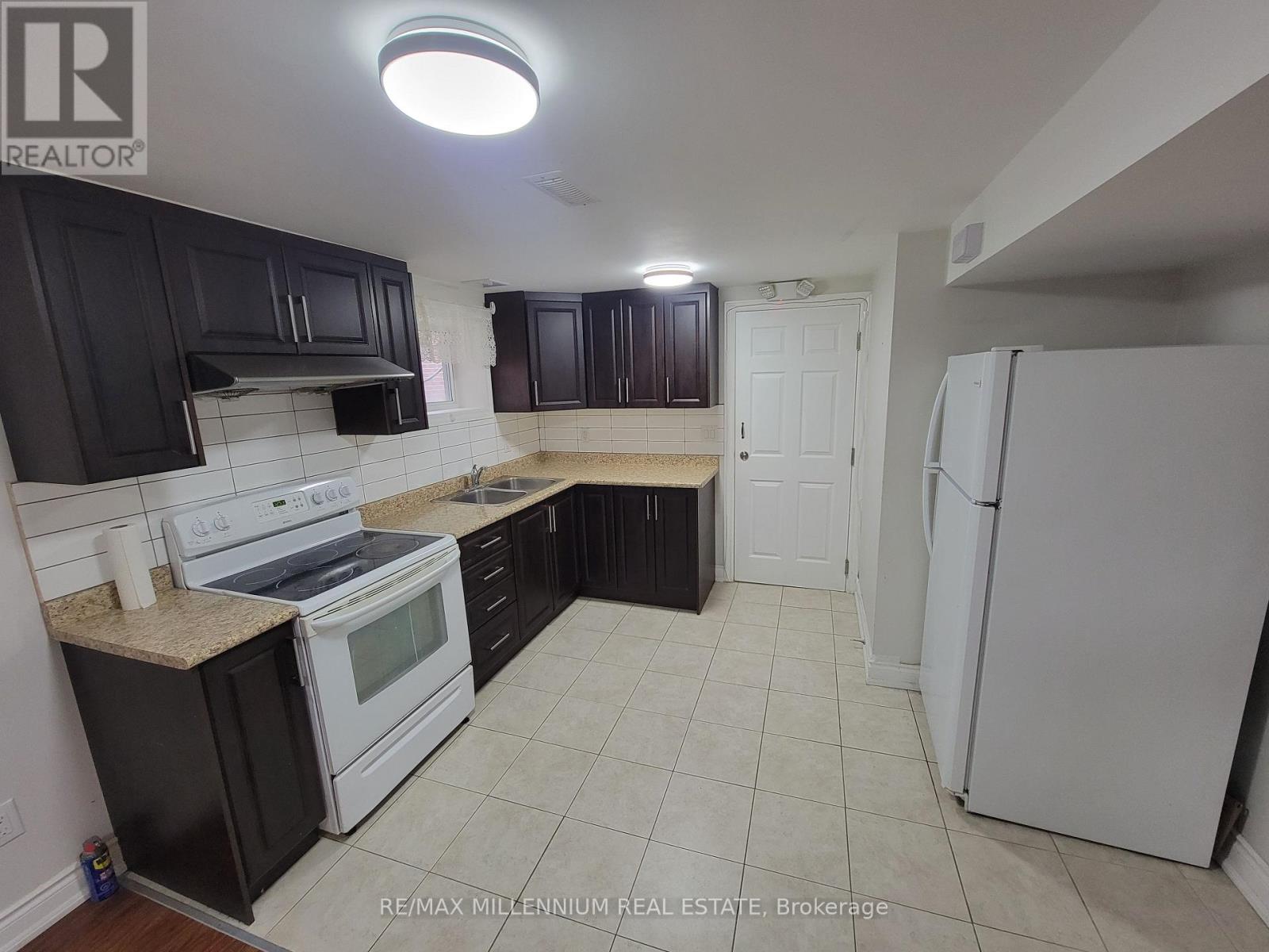 A kitchen with black cabinets and white appliances.