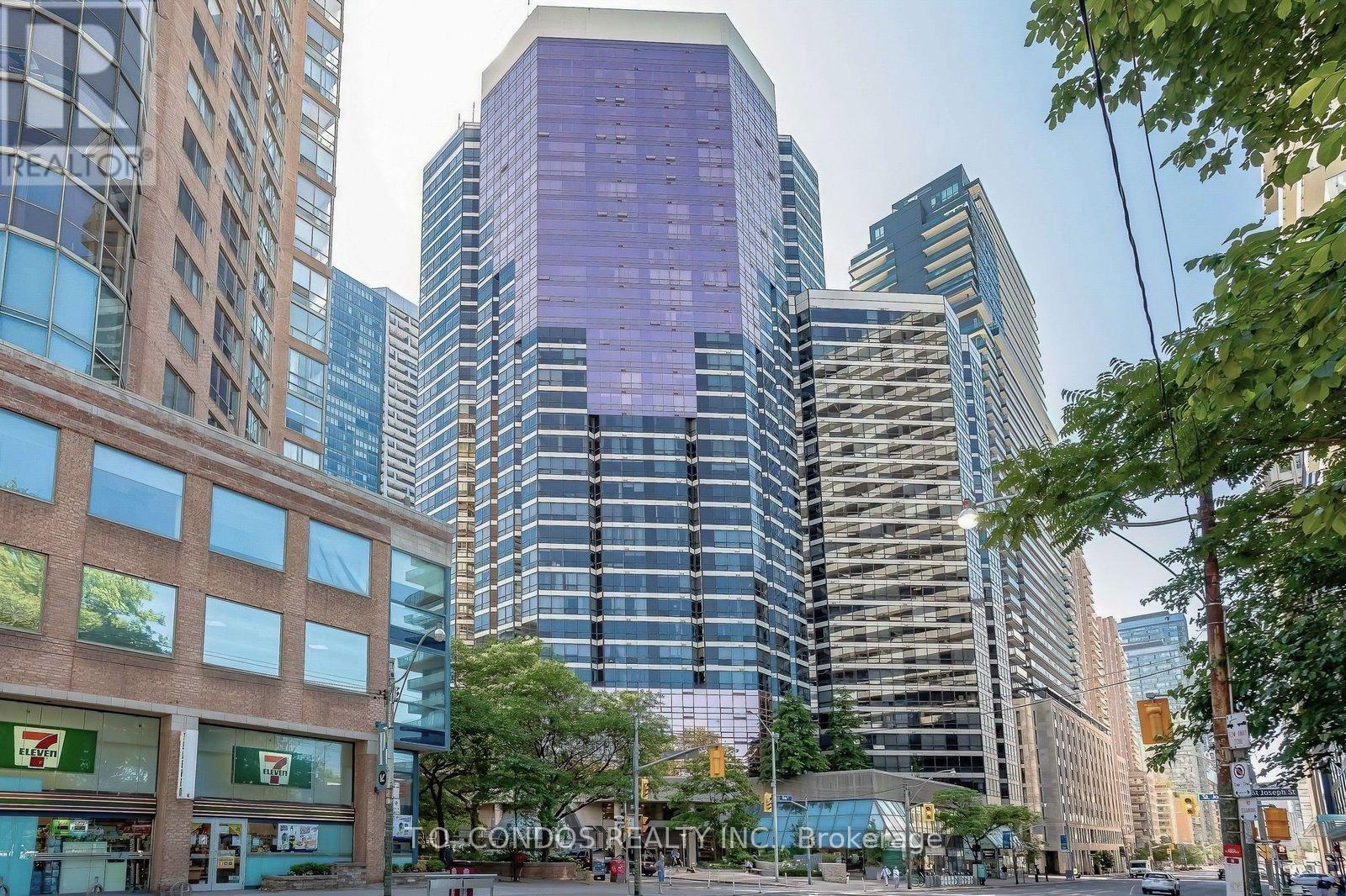A tall building with a purple tinted glass facade stands in front of other buildings.