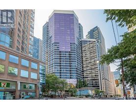 A tall building with a purple tinted glass facade stands in front of other buildings.