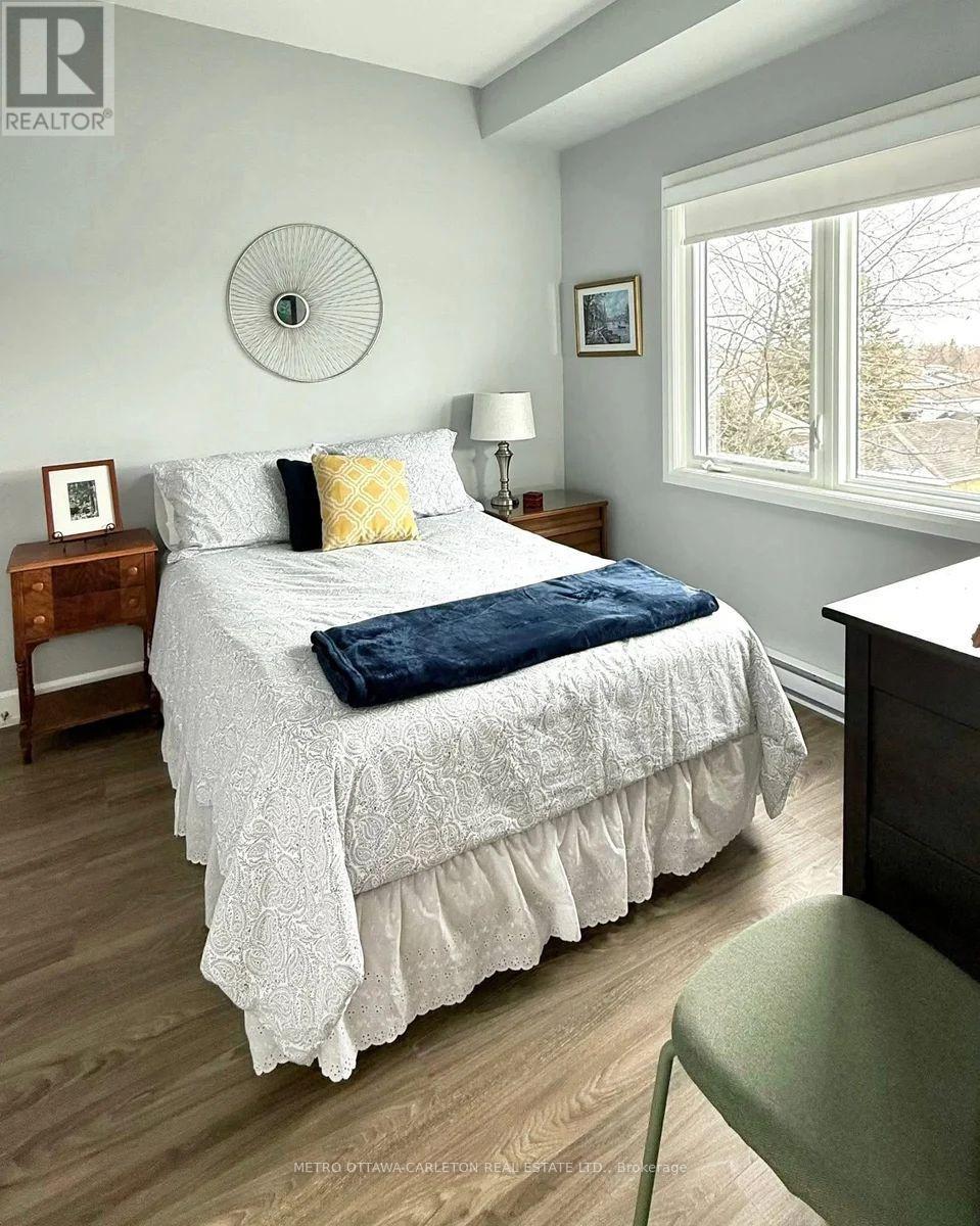 A bedroom with a bed, nightstand, and chair.