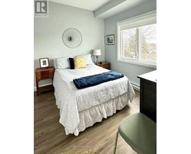 A bedroom with a bed, nightstand, and chair.