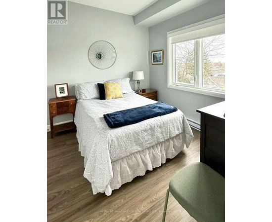 A bedroom with a bed, nightstand, and chair.