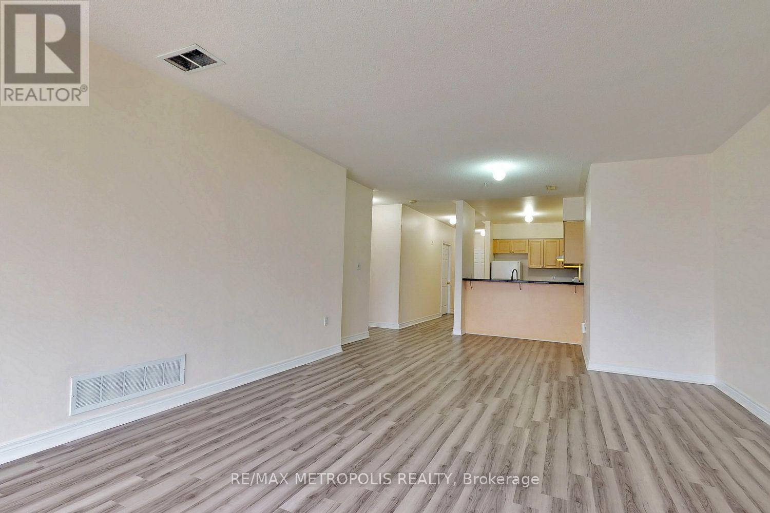 A spacious room with wooden flooring and white walls.