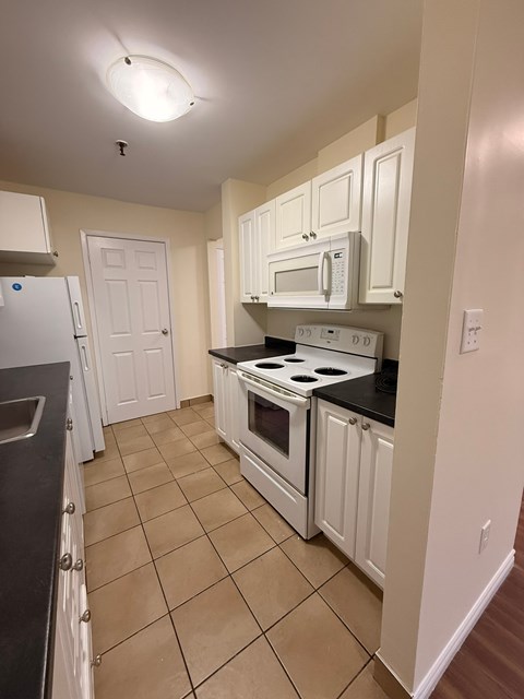A kitchen with white cabinets and a black stove top.