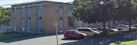 A no parking sign is on a pole in front of a building.