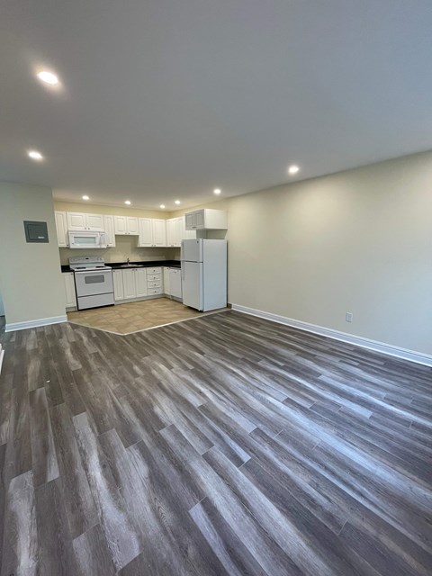 A kitchen with white cabinets and a microwave is visible through a glass door.