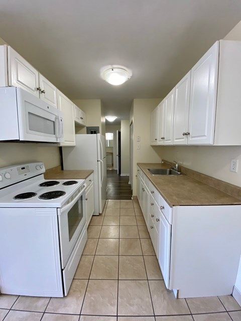 A kitchen with white appliances and cabinets.