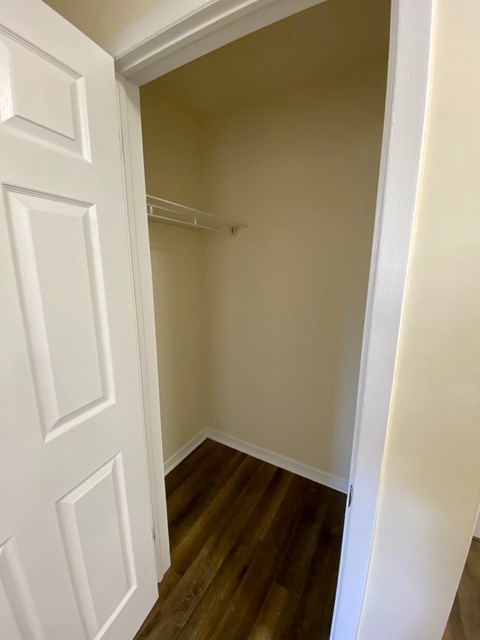 A white door is open to a room with a wooden floor.
