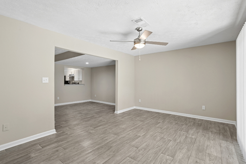 A room with a ceiling fan and light fixture, and a wooden floor.