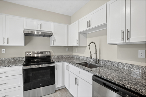 A kitchen with white cabinets and granite countertops.
