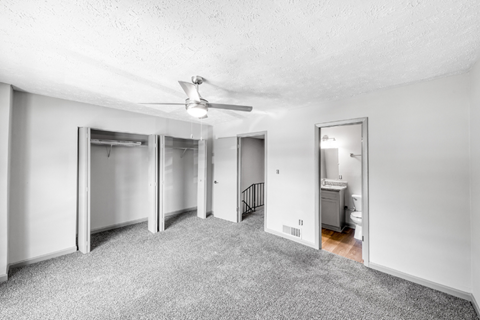 A spacious room with a ceiling fan and a bathroom visible through an open door.