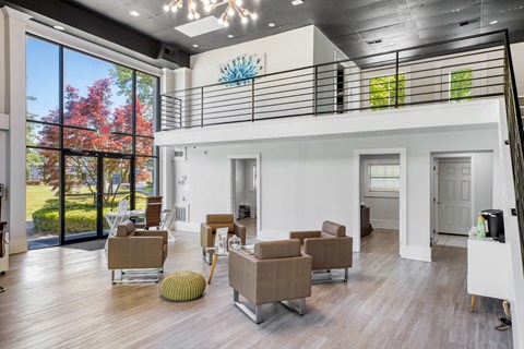 A modern living room with a balcony and a view of trees.