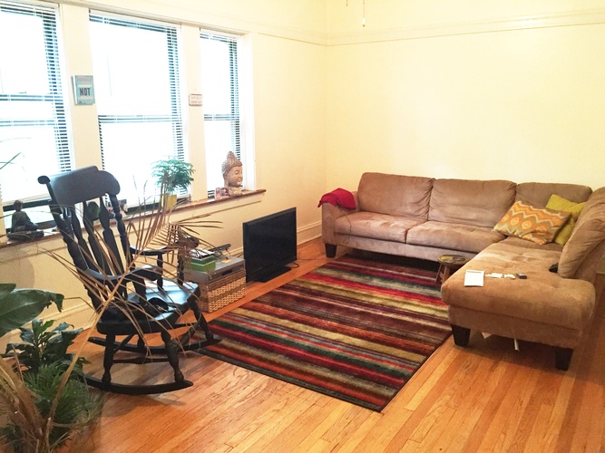 A living room with a brown couch, a chair, and a rug.