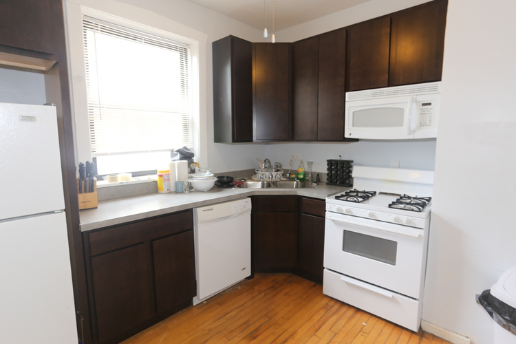 A kitchen with white appliances and brown cabinets.