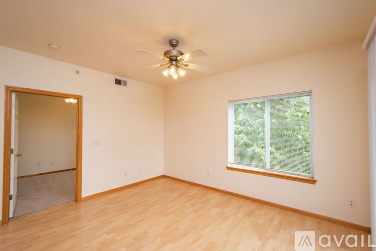 A room with wooden floors and a window showing greenery outside.