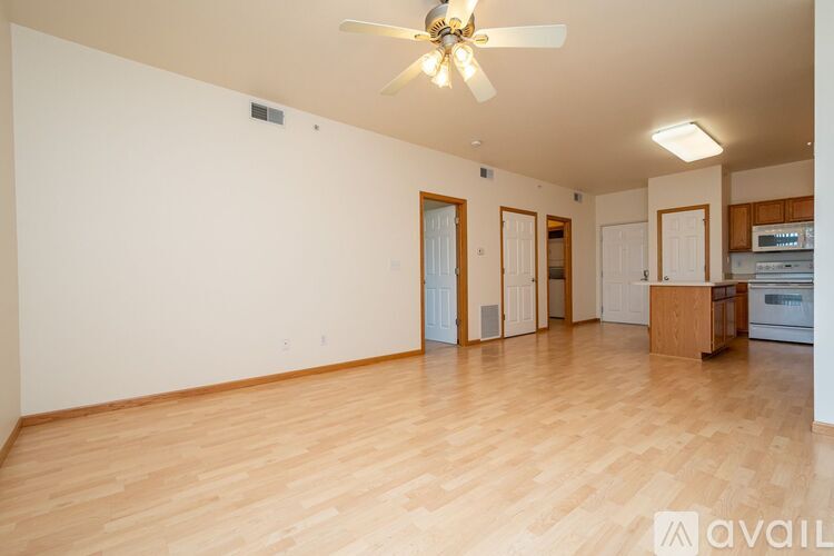 A spacious room with wooden flooring and a ceiling fan.