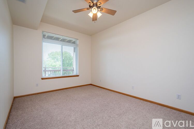 A room with a ceiling fan and a window with a view of trees.