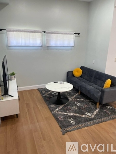 A living room with a grey couch, a white coffee table, and a TV on a white stand.
