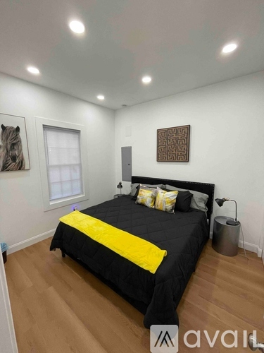 A bedroom with a black bed and a yellow pillow.