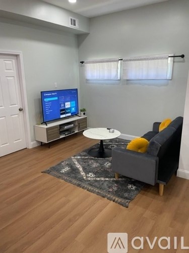 A living room with a grey couch, a white table, and a television on a stand.