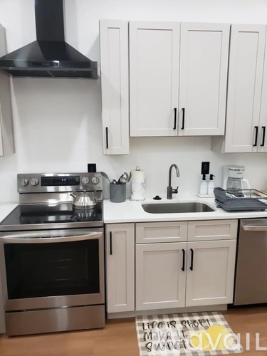 A kitchen with white cabinets and a black range hood.