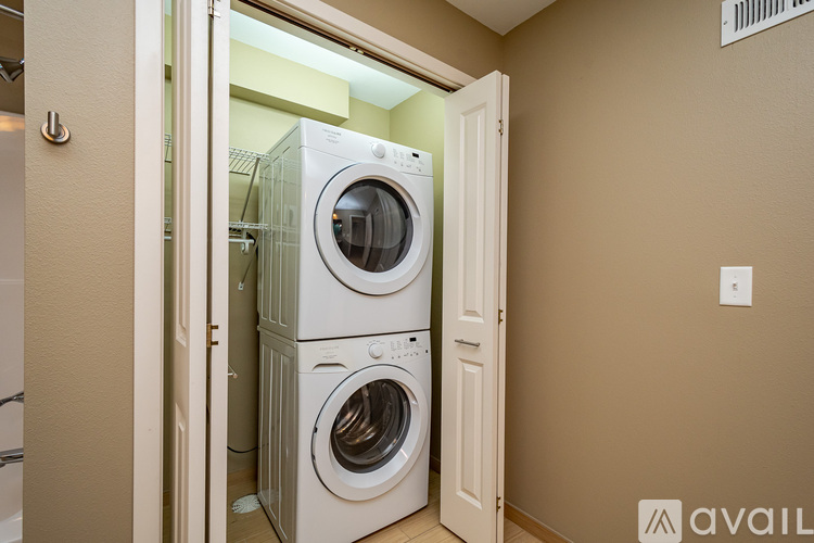 A stack of two white front loading washing machines is in a doorway.