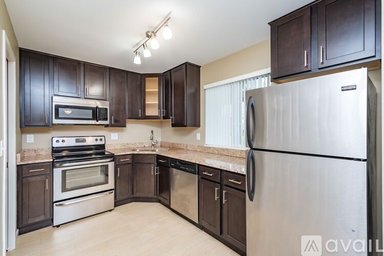 A kitchen with dark brown cabinets and stainless steel appliances.