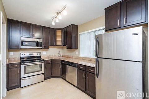 A kitchen with dark brown cabinets and stainless steel appliances.