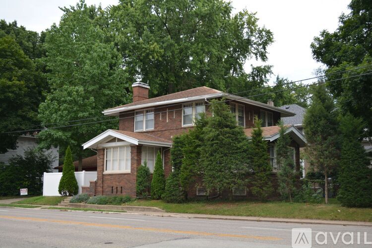 A house with a brown roof and a white fence in front of it.