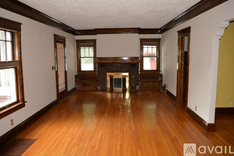 A large empty room with wood floors and a fireplace.