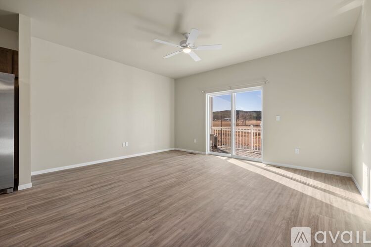 A spacious room with a ceiling fan and sliding glass doors leading to a balcony.