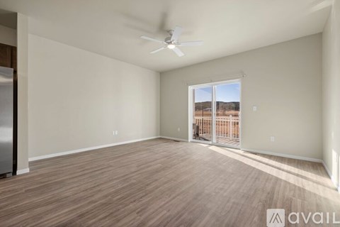 A spacious room with a ceiling fan and sliding glass doors leading to a balcony.