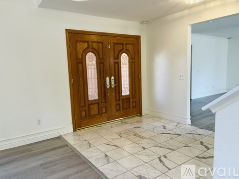 A wooden door with glass panels and a white wall behind it.