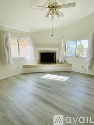 A spacious living room with a fireplace and a ceiling fan.